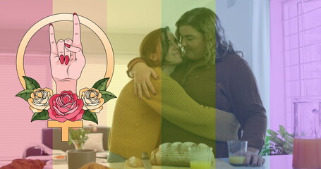 Image of rainbow flag and hand with roses over lesbian couple embracing at home