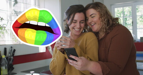 Image of rainbow lips over lesbian couple drinking coffee and using smartphone
