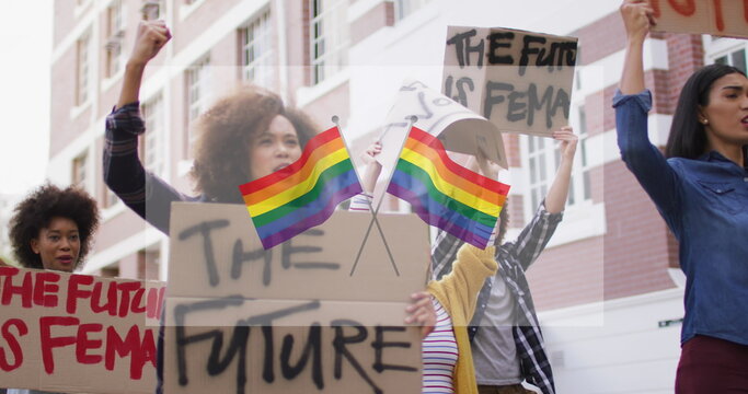 Image of rainbow flags over diverse protesters with banners