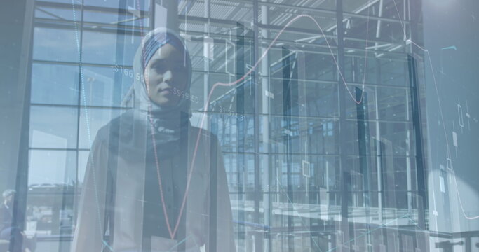 Image of financial graphs over biracial businesswoman in hijab walking in office