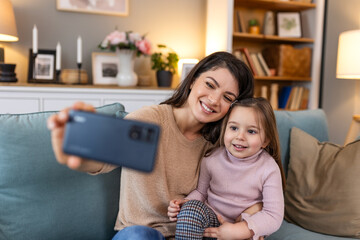 Little daughter young mother faces webcam close up view. Mom with adorable kid girl use smartphone...