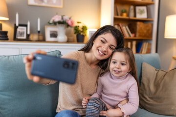 Little daughter young mother faces webcam close up view. Mom with adorable kid girl use smartphone have fun making selfie photography, vloggers record new vlog, enjoy funny activity concept