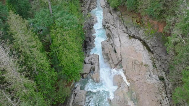 Slow motion Cinematic nature of Washington mountain park, copy background 4K. Powerful waterfall among large wet mountains boulders in green spruce forest. Aerial narrow fast splashing river flow USA