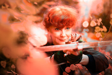 Mature model portraying a royal huntress with red curve hair is hunting with a crossbow in the in...