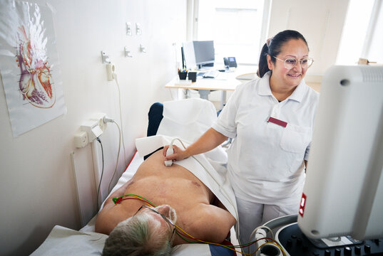 Senior man getting ultrasound done by female doctor in examination room
