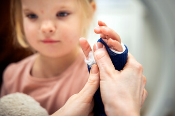 Cropped image of female pediatrician holding hand of girl with physical injury