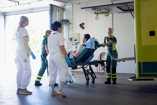 Female paramedics and nurses pushing male patient on gurney for emergency treatment in hospital