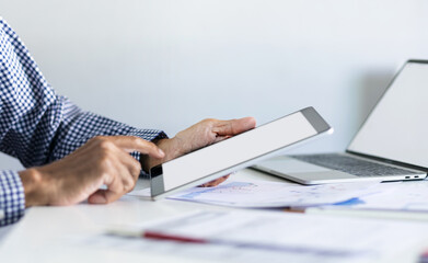 Businessman in office using tablet with documents and chart for analyzing data of investment to make investment plan for a future, financial investment concept.