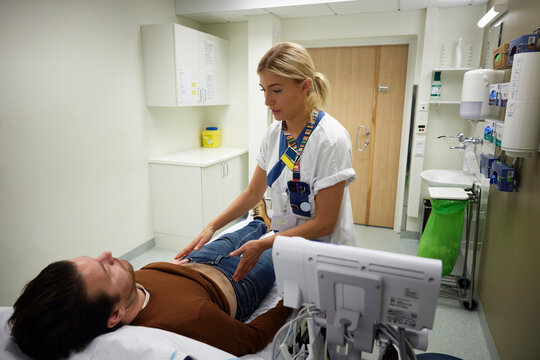 Female doctor examining male patient lying on bed in examination room