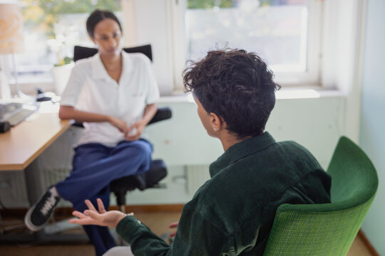Teenage boy taking advice from male counselor while sitting in office