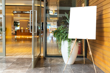 A photo of a blank white canvas on an artist's easel in a studio. The canvas is in a vertical...