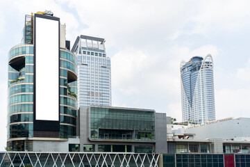 Large white billboard on the side of a building in Bangkok, Thailand. Billboard is located in a busy commercial area and is surrounded.