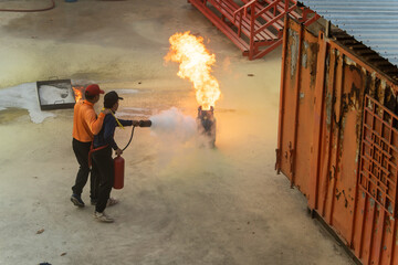 Firefighters are practicing using a fire extinguisher to extinguish a fire caused by a gas tank used for cooking.