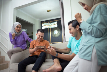 Portrait of young people sitting on the couch and playing games on mobile phones spending time together