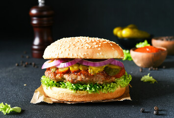 Hamburger with beef and pickled cucumbers and lettuce on the background