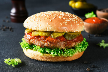 Hamburger with beef and pickled cucumbers and lettuce on the background