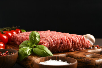 Minced pork and beef on a wooden board. Minced meat with spices on a dark background