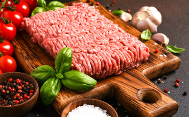 Minced pork and beef on a wooden board. Minced meat with spices on a dark background