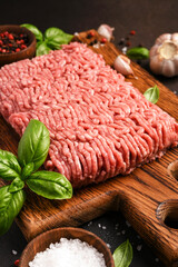 Minced pork and beef on a wooden board. Minced meat with spices on a dark background