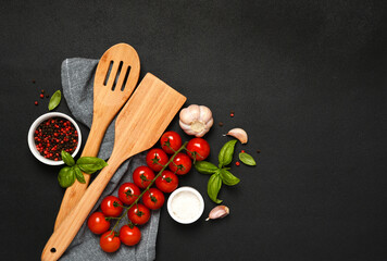 Spatula and kitchen towel and tomatoes on a black background. Food background - 752041702