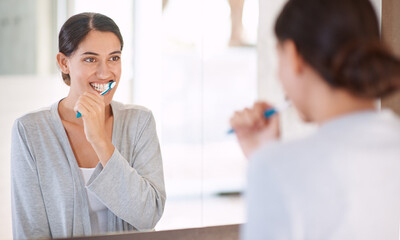 Woman, brushing teeth and happy in home by mirror for health, wellness or self care for breath in...