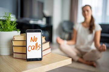 Digital detox concept. In the foreground is a smartphone with the text No Calls and woman...