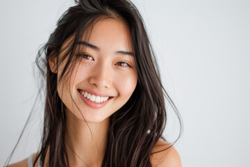 Beautiful studio portrait of young, stylish asian woman, long hair, smiling and looking at camera with confidence on white background