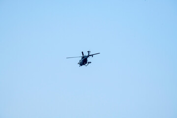 Combat helicopter is flying on isolated blue sky.