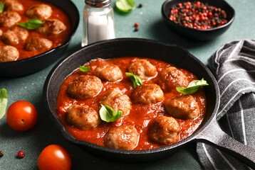 .Meatballs with tomato sauce and basil in a frying pan