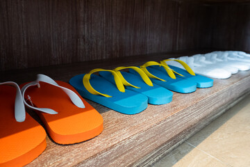 Collection of bright slippers in orange, blue with yellow strap, and white beachwear fashionable in...