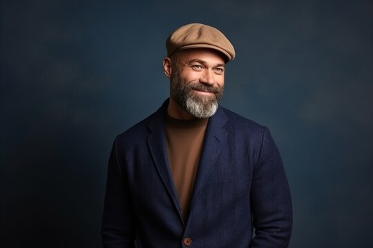 Handsome bearded man wearing a cap and jacket on a blue background