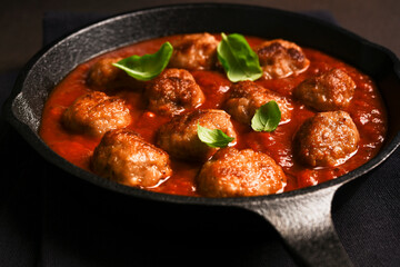 .Meatballs with tomato sauce and basil in a frying pan
