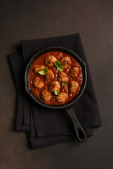 .Meatballs with tomato sauce and basil in a frying pan