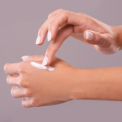Hands, cream and beauty with woman for skincare, dermatology and wellness on grey background. Moisturizer, lotion or sunscreen with nails and manicure, antiaging cosmetic product and skin health