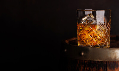 Whiskey glass with ice on a rustic barrel, a classic sip