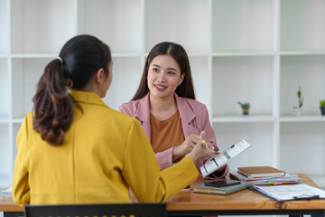Two Young Asian businesswoman discuss with new startup project Idea presentation, analyze planning and financial statistics and investment market at office.