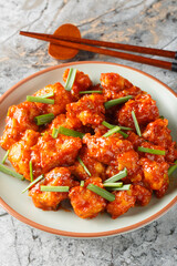 Gobi Manchurian pairs crispy cauliflower with a sweet, tangy Indo-Chinese sauce closeup on the plate on the table. Vertical