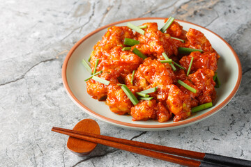 Gobi Manchurian is a popular appetizer made with fried cauliflower coated in umami chili sauce closeup on the plate on the table. Horizontal