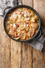 Morbradboffer i flodesovs pork tenderloin with onions, bacon and mushrooms in a creamy sauce closeup on the pan on the table. Vertical top view from above