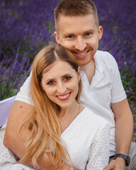 happy couple sits on a bench and hugs on a lavender field