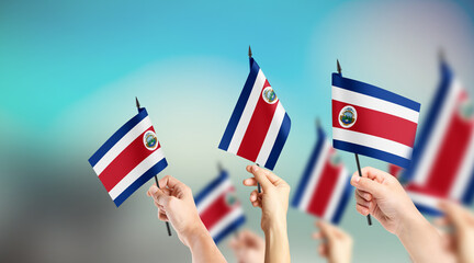 A group of people are holding small flags of Costa Rica in their hands.