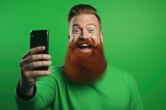 Photo of positive cheerful man with ginger beard dressed green t-shirt making selfie recording video isolated on green color background