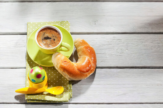 Breakfast with coloured Easter egg, cup of coffee and pastry