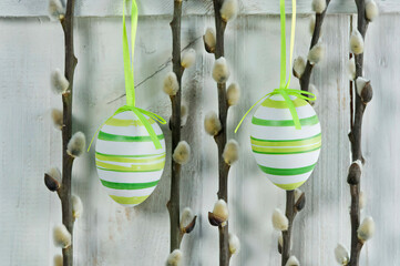 Easter eggs with pussy willow twigs hanging on wall - obrazy, fototapety, plakaty