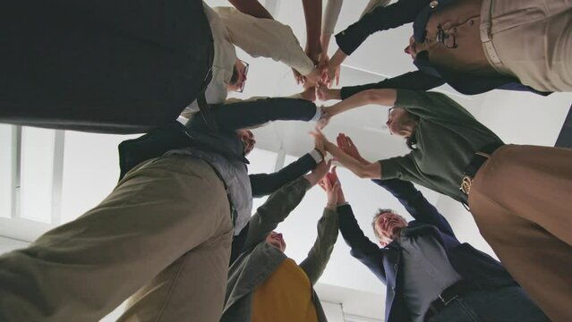 Corporate team joining hands together in a symbol of unity and teamwork after a successful meeting in a modern office