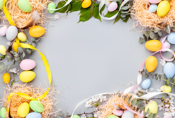 Stylish background with colorful easter eggs isolated on gray background with green eucalyptus plants. Flat lay, top view, mockup with copy space, overhead, template