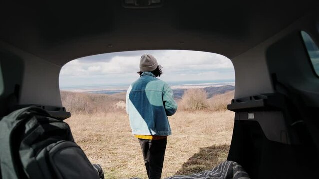 Cinematic footage shot through the trunk of an SUV. A young woman enjoying the view during her solo road trip.