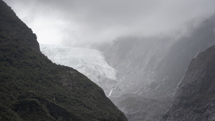 Massive glacier flowing into a valley through steep rock walls shot in New Zealand