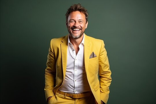 Portrait of a smiling man in yellow suit standing against green background