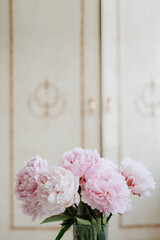 bouquet of soft pink peonies against a background of vintage furniture, photo in pastel colors